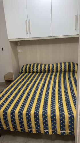 a bed with a yellow and blue striped comforter in a room at Home Giove in Giardini Naxos