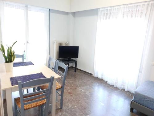 ein Esszimmer mit Tisch und Stühlen und einem Fernseher in der Unterkunft Γωνιακό φωτεινό δωμάτιο in Athen