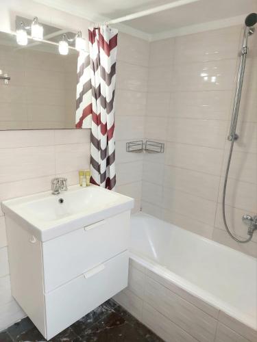 a white bathroom with a sink and a bath tub at Γωνιακό φωτεινό 3κλινο δωμάτιο in Athens