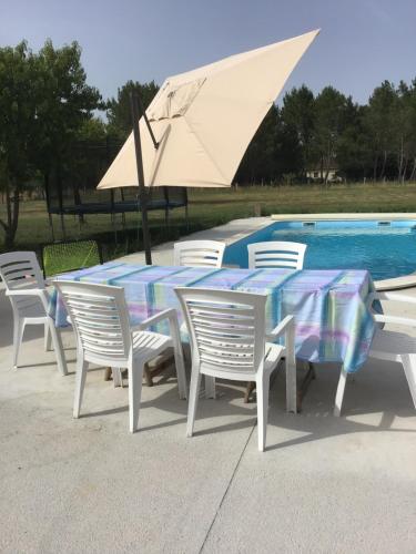 une table et des chaises avec un parasol à côté d'une piscine dans l'établissement Une maison entière de 4-5 pers avec piscine, à Le Pizou