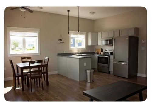 a kitchen and dining room with a table and a refrigerator at Gros Morne Coastal Suites in Rocky Harbour