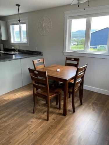 a dining room with a wooden table and chairs at Gros Morne Coastal Suites in Rocky Harbour