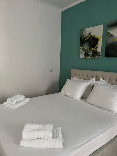 a white bed with two towels on top of it at Vrenjo GuestHouse in Gjirokastër