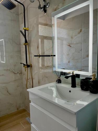 a bathroom with a white sink and a mirror at Vrenjo GuestHouse in Gjirokastër