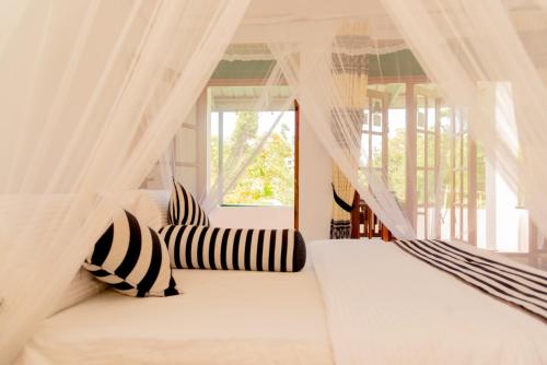a bedroom with a white bed with black and white pillows at Samiru Guest Inn Ella in Ella