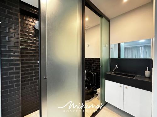 a bathroom with a sink and a glass shower door at Get By Side - Jardim Oceania in Tambaú