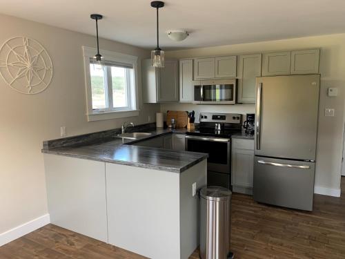 a kitchen with white cabinets and a stainless steel refrigerator at Gros Morne Coastal Suites in Rocky Harbour