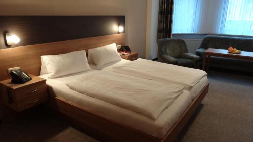 ein Hotelzimmer mit einem großen Bett und einem Stuhl in der Unterkunft Pension Villa Irene in Bad Harzburg
