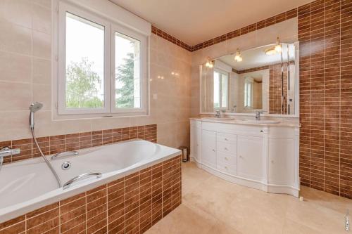 a bathroom with a tub and a sink and a mirror at La maison de Gradille - Piscine in Lisle-sur-Tarn