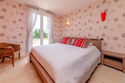 a bedroom with a bed with red pillows and a window at La maison de Gradille - Piscine in Lisle-sur-Tarn