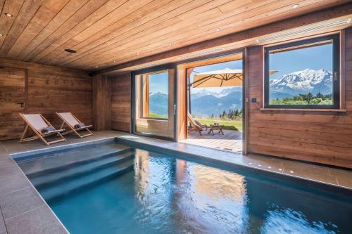 une maison avec une piscine offrant une vue sur les montagnes dans l'établissement Chalet 14 personnes I Luxe I Piscine & Sauna I Salle cinéma I Le Chalet Club, à Combloux