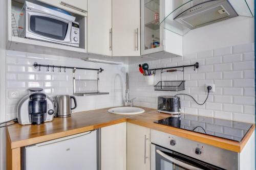 une petite cuisine avec des armoires blanches et un micro-ondes dans l'établissement Appartement agréable à Bordeaux, à Bordeaux
