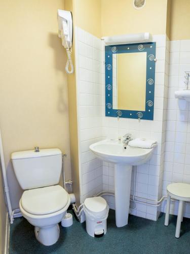 a bathroom with a toilet and a sink and a mirror at Hôtel de la Vendée in La Roche-sur-Yon