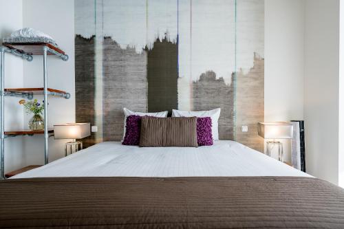 a bedroom with a large bed with two lamps at Boutique Hotel De Eilanden in Harlingen