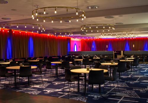 comedor con mesas y sillas y cortinas rojas y azules en Grand Hotel Lapland, en Gällivare