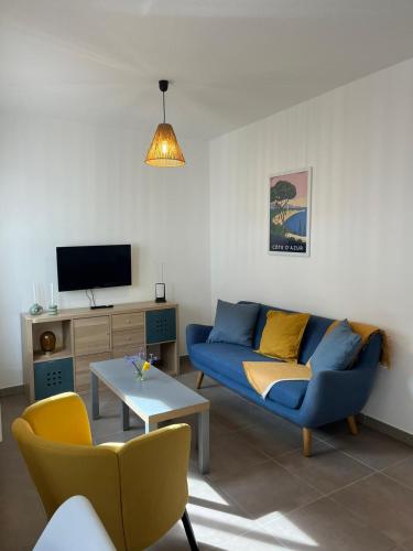 un salon avec un canapé bleu et une télévision dans l'établissement Pinède carqueiranne, à Carqueiranne