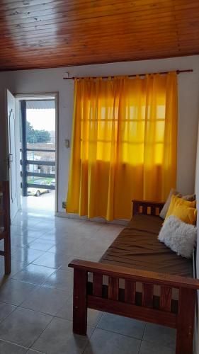 a bedroom with a bed with a yellow curtain at Hospedaje Navarro Dpto N3 matrimonial in Navarro