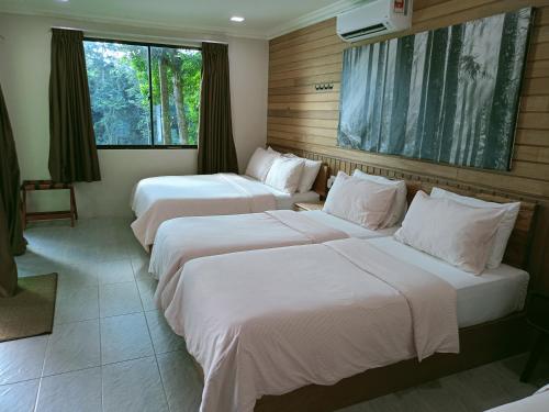 two beds in a hotel room with white sheets at Naura Roomstay in Kuala Tahan