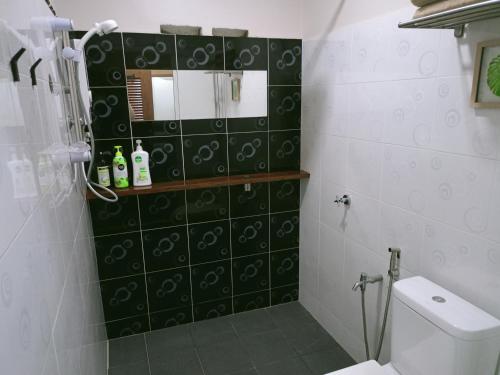 a bathroom with a toilet and a green tile wall at Naura Roomstay in Kuala Tahan