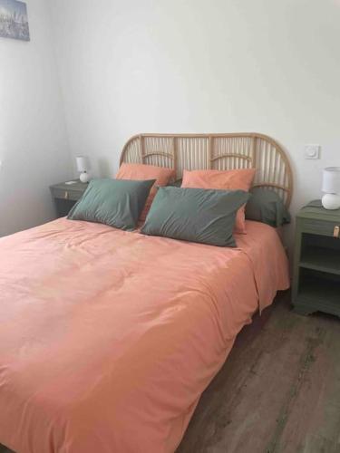 - un lit avec une couette en orange et 3 oreillers dans l'établissement Le Porge location T2 neuf, à Le Porge