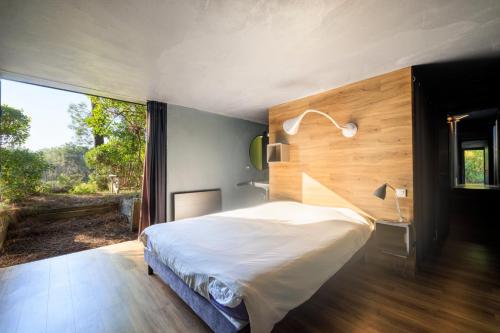 une chambre avec un grand lit et une grande fenêtre dans l'établissement Villa Lodge Plage et golf à pieds, à Moliets-et-Maa