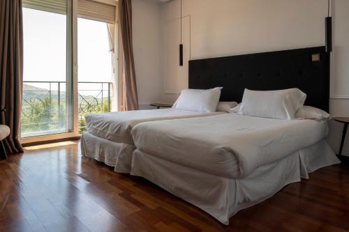 a large white bed in a room with a large window at Hotel Hita "Nature Experience" for all in Navacerrada