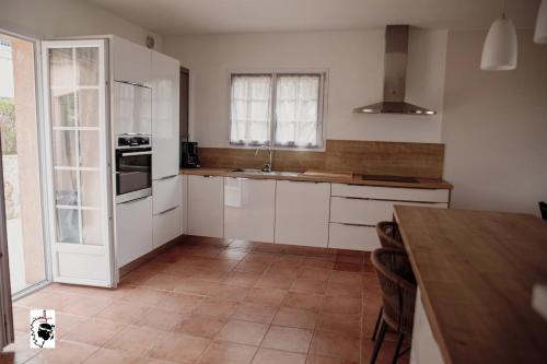 une cuisine avec des armoires blanches et une table en bois dans l'établissement La Casa Gianni, à Ajaccio