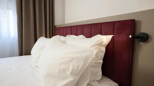 a bed with a red headboard and white pillows at Circle Tirana City Center in Tirana