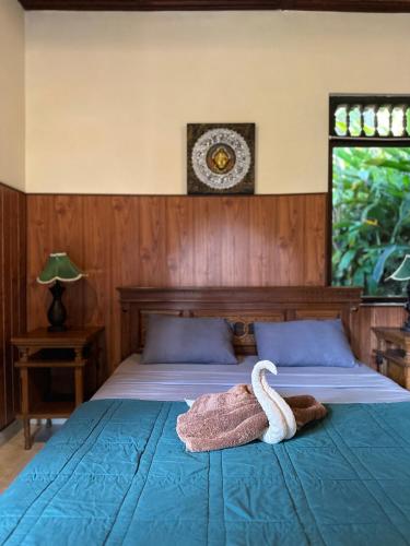 a bedroom with a bed with a swan towel on it at Kajeng Bungalow in Ubud