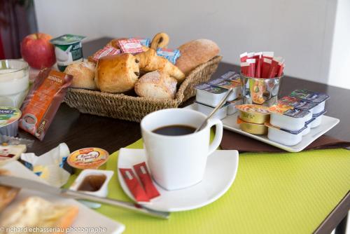 a cup of coffee sitting on a table with bread at Hôtel de la Vendée in La Roche-sur-Yon