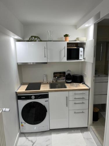 une cuisine blanche avec un évier et un micro-ondes dans l'établissement Logement lina - proche paris et Orly, à Palaiseau