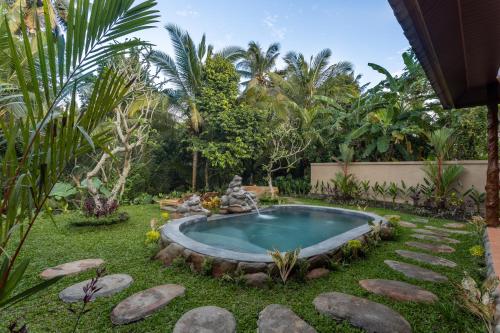 a small pool in a garden with rocks around it at Royal Amertha Ubud Jungle View in Gianyar