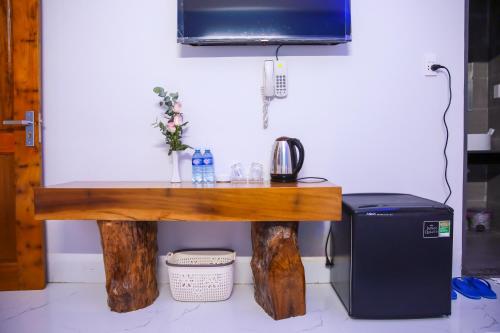a wooden table with a television and a refrigerator at Quốc Hùng Hotel in Tam Ky