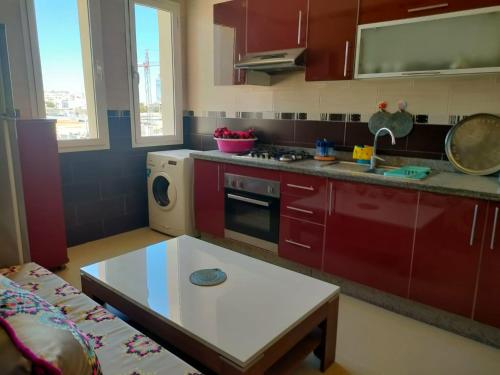 a kitchen with red cabinets and a table in it at Appartement spacieux et ensoleillé en bord de mer in Aït Saïd