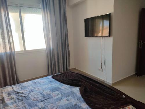 a bedroom with a bed and a flat screen tv at Appartement spacieux et ensoleillé en bord de mer in Aït Saïd