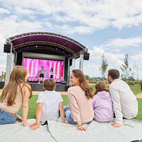 a group of people sitting on the ground watching a stage at Lovely Static Caravan at Billing Aquadrome in Great Billing