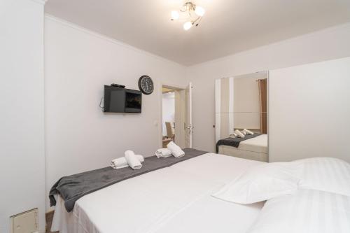 een witte slaapkamer met een groot bed en een tv bij House Terra Madre in Gruda