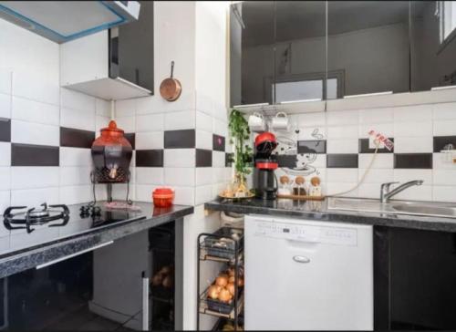 a kitchen with black and white tiled walls at Appartement aux portes de Paris in Villejuif