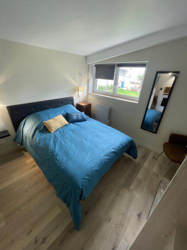 a bedroom with a blue bed and a mirror at Plage des Sables d'or in Broons