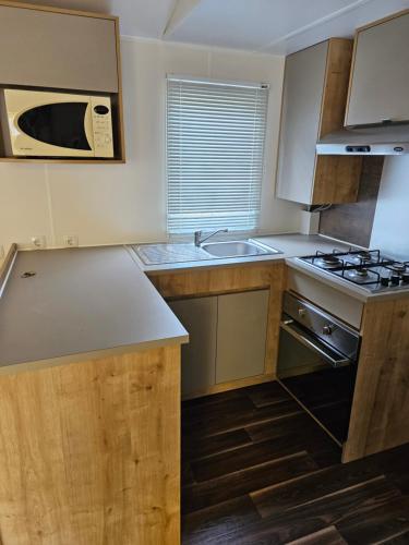 une petite cuisine avec un évier et une cuisinière dans l'établissement Mobilhome, à Quend