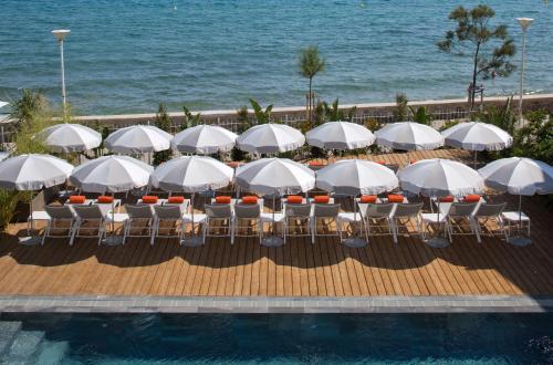 - un groupe de tables et de chaises avec parasols au bord de la piscine dans l'établissement Grand Hotel Des Sablettes Plage, Curio Collection By Hilton, à La Seyne-sur-Mer