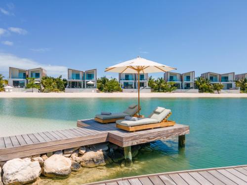a dock with two chairs and an umbrella in the water at South Bank in Long Bay Hills