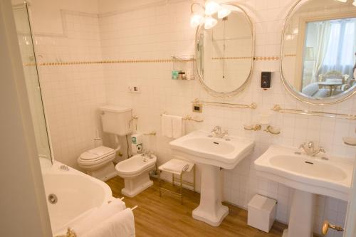 a bathroom with two sinks and a toilet and a mirror at Hotel Villa Stucky in Mogliano Veneto