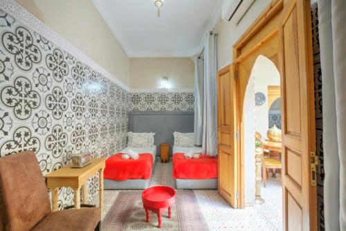 a small room with two beds and a table at Riad Inaka in Marrakech