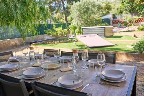 a wooden table with plates and wine glasses on it at La Provençale - Jacuzzi, BBQ, jardin & clim in Toulon