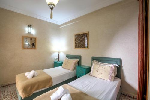 a hotel room with two beds and a window at Riad Inaka in Marrakech