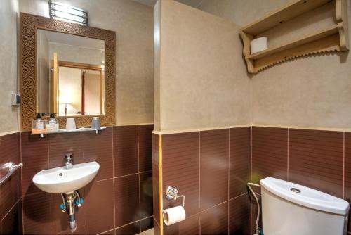 a bathroom with a sink and a toilet and a mirror at Riad Inaka in Marrakech