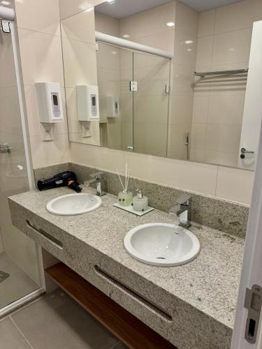 a bathroom with two sinks and a large mirror at Sensacional Flat Serra Class - vista do Pôr do Sol in Canela