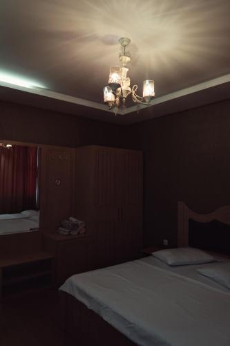 a dark room with two beds and a chandelier at Hotel Antika in Peje