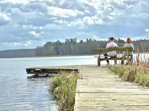 a couple sitting on a bench overlooking a lake at Zacisze Mazurskie nad Jeziorem in Sędańsk